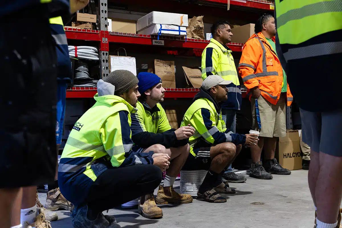A group of trades men listening to a team meeting