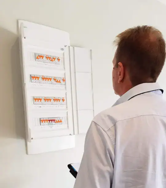 Electrician testing an RCD for tripping at the switchboard