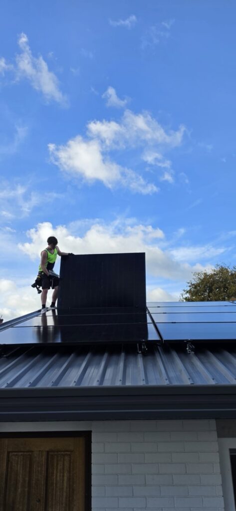 Registered electrician installing a solar power system on an Auckland roof